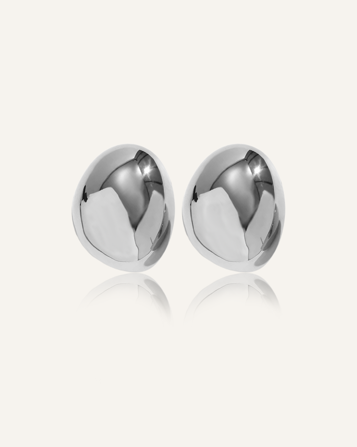 Mona Earrings in silver with bold oval dome design, laid flat on white surface.