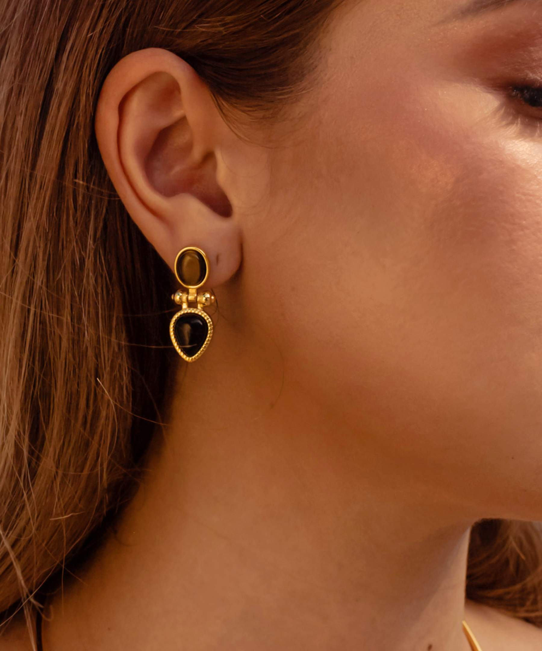 Closeup of model wearing Nadia Earrings featuring tiger eye stone.
