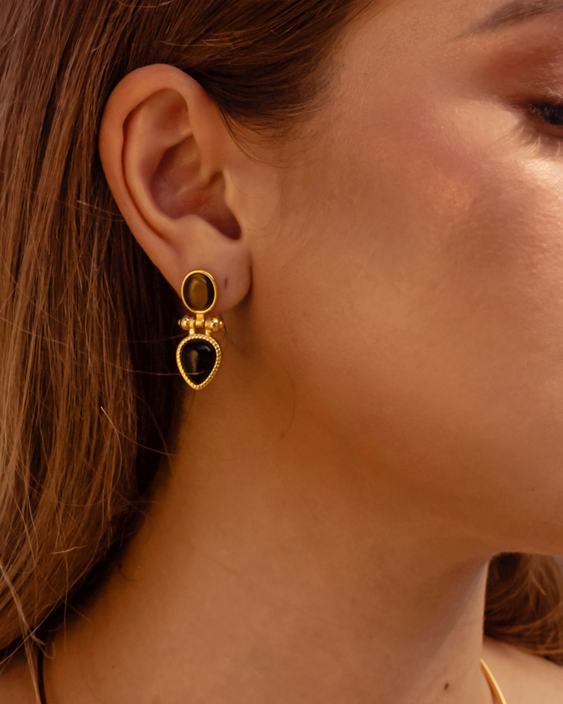 Closeup of model wearing Nadia Earrings featuring tiger eye stone.