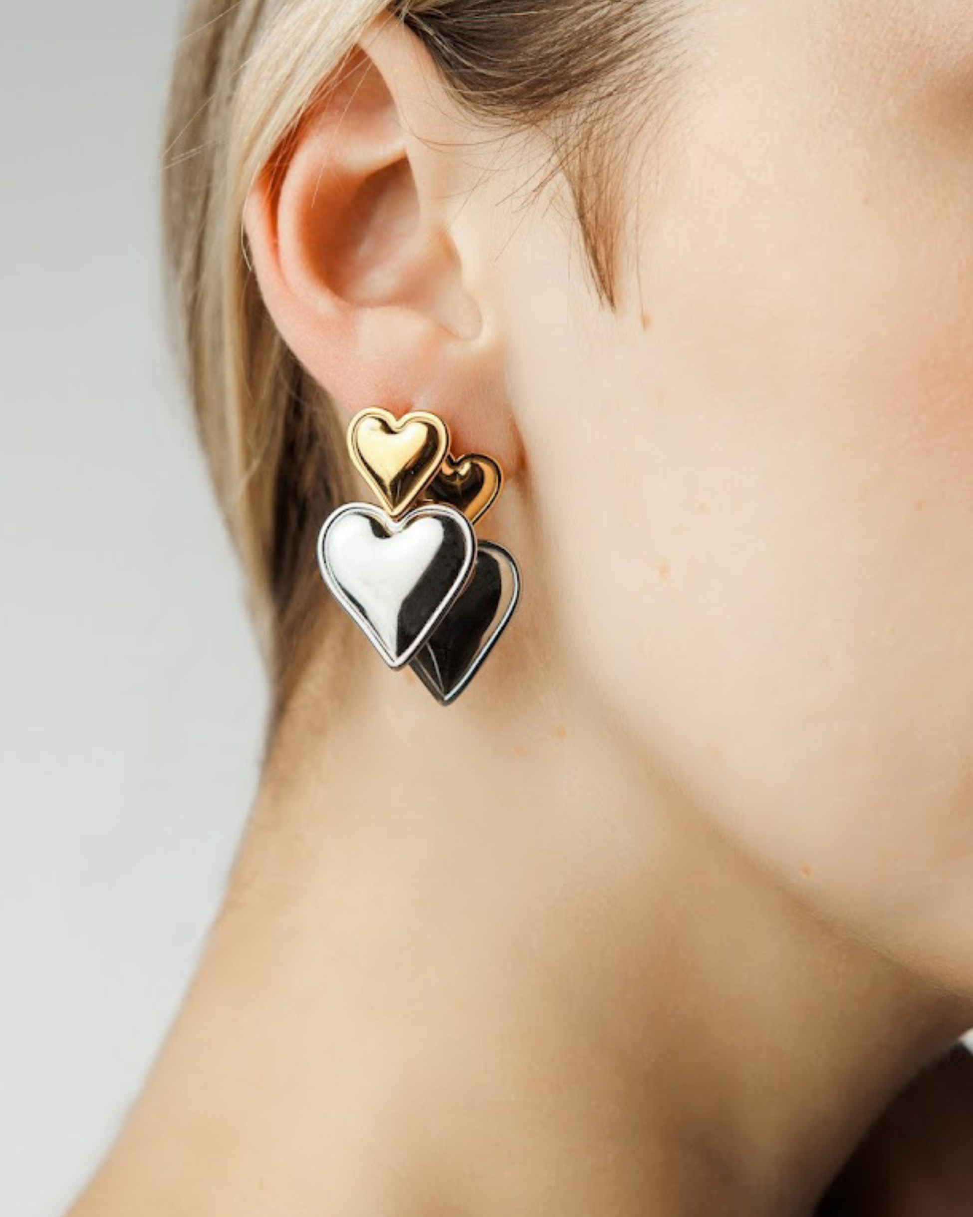 Close-up of Sadie Earrings showing gold heart atop silver heart detail.