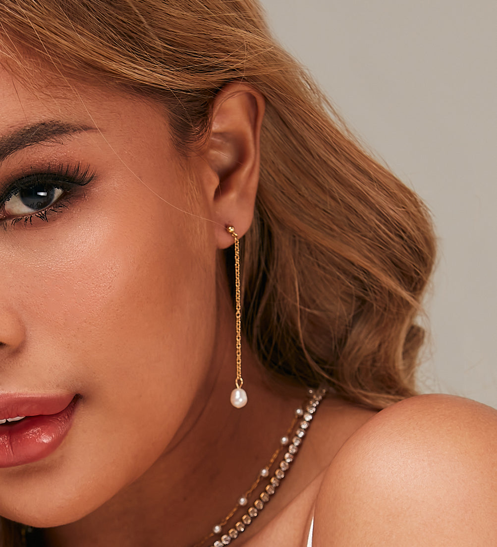 Closeup of Corine Earrings worn, highlighting pearl drop and gold chain.