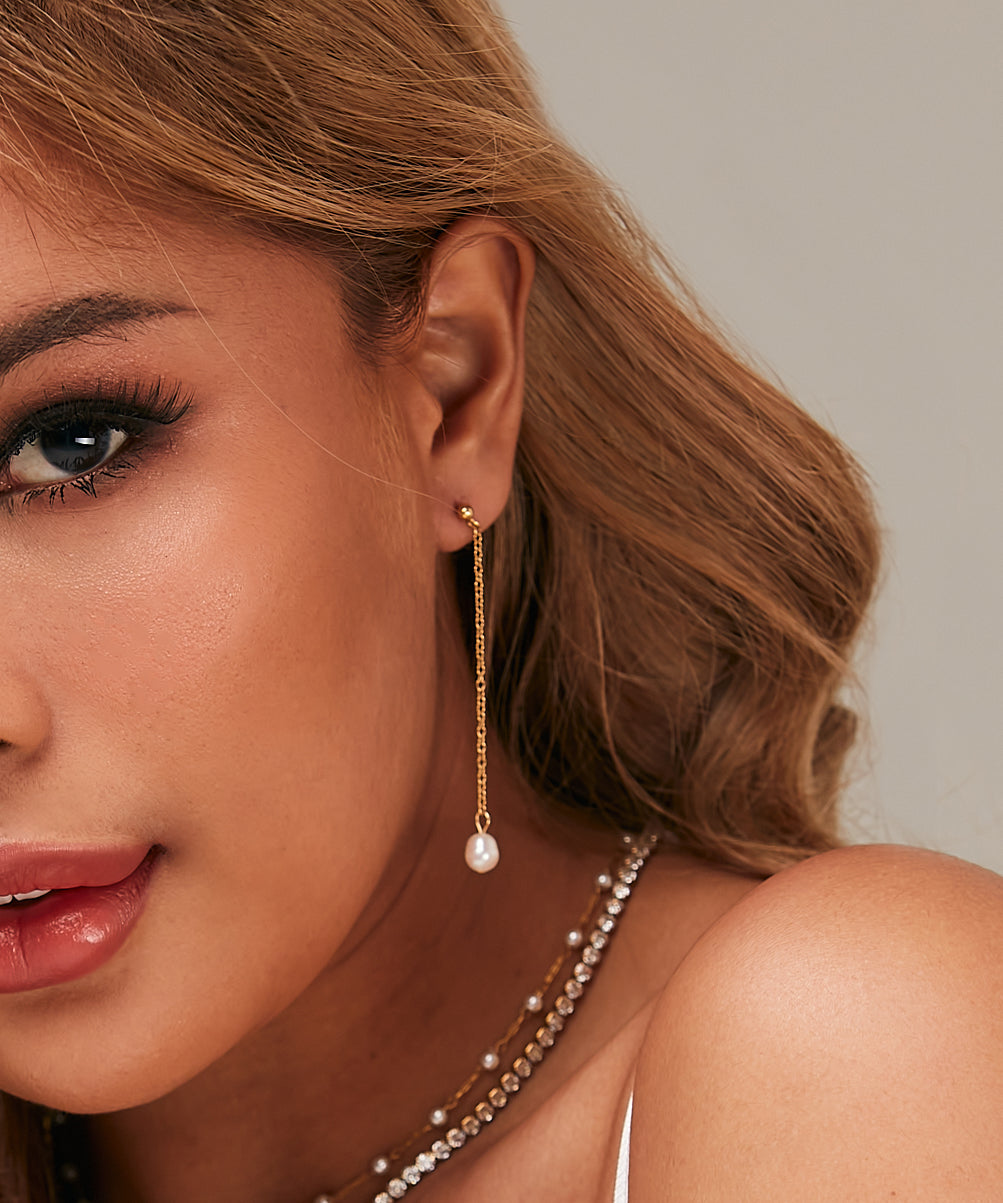 Closeup of Corine Earrings worn, highlighting pearl drop and gold chain.
