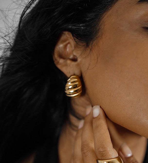 Closeup of Demi Earrings worn on ear, highlighting twisted hoop style.