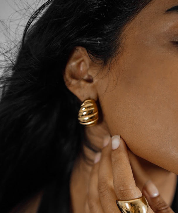 Closeup of Demi Earrings worn on ear, highlighting twisted hoop style.