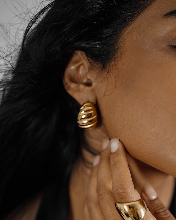 Closeup of Demi Earrings worn on ear, highlighting twisted hoop style.