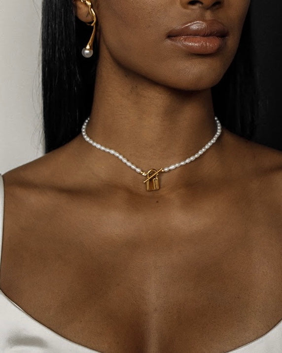 Closeup view of the Lily Necklace on neck highlighting padlock pendant and pearl choker design.