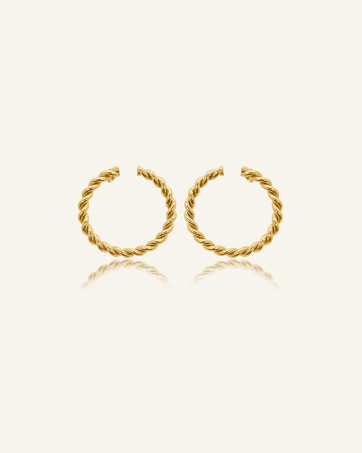 Selene Earrings flatlay showing twisted circular gold hoop design.